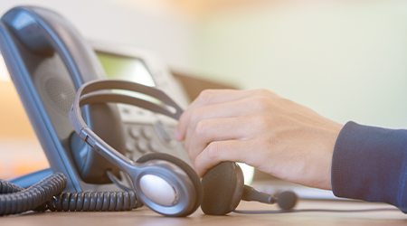 A close up image of a businessman picking up phone headset.