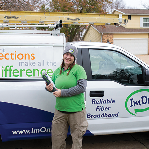 ImOn female install technician standing in front of an ImOn truck ready to start Internet install at customer's home.