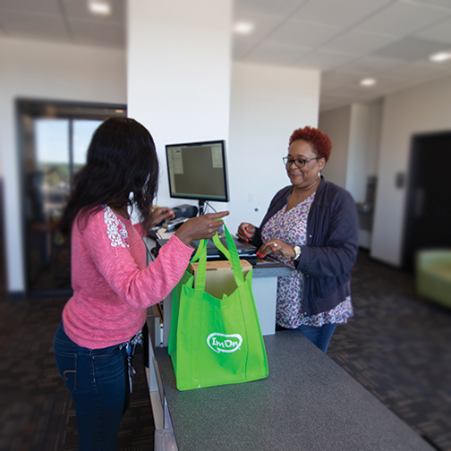 ImOn Customer Care representative helping a customer answer a question at the front desk.