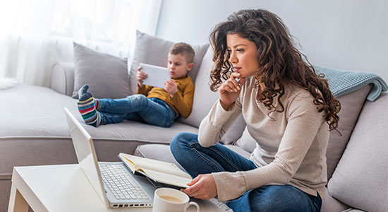 A young boy and girl laying on the living room floor playing on their tablet.