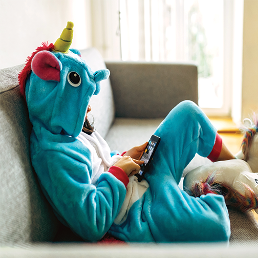 A child wearing a unicorn PJs playing on his tablet.