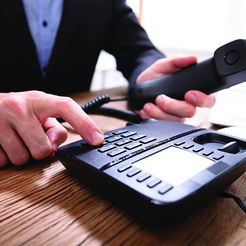 A close up shot of an business man lifting phone receiver and calling. 