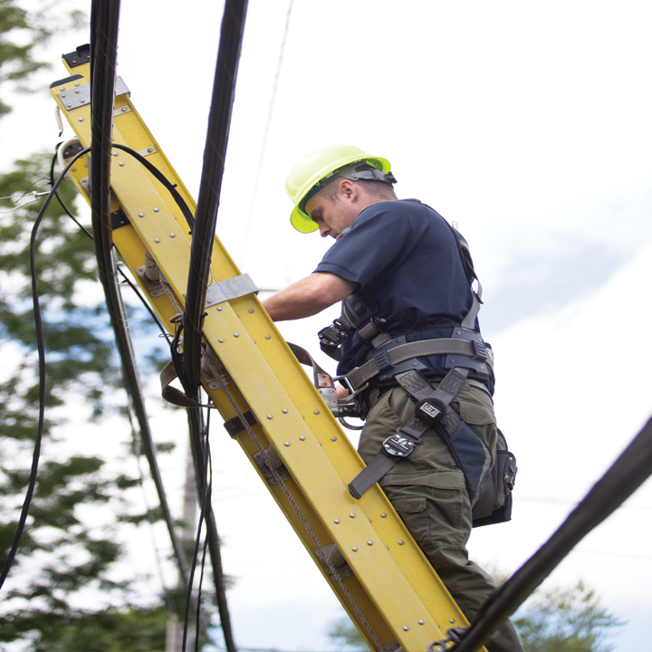 ImOn residential install technician on a ladder against a pole working on network fiber.