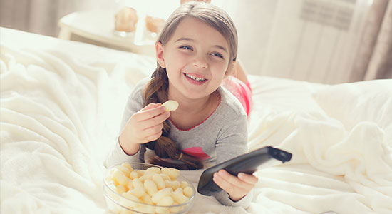 A young boy and girl laying on the living room floor playing on their tablet.