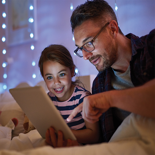 Father and daughter looking at content on a tablet.