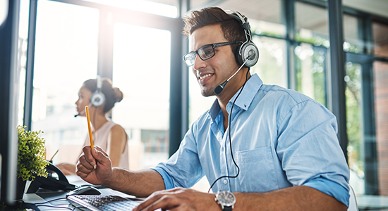 Office employee talking on phone headset while working at computer.