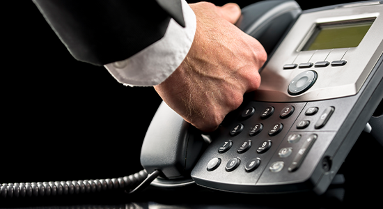 Business man reaching for receiver on office phone. 